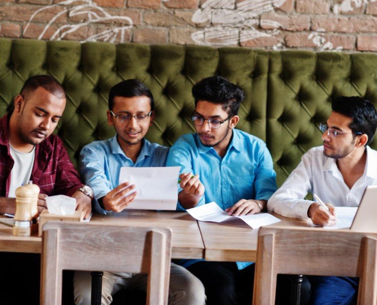 4 Indian men sitting in a cafe discussing